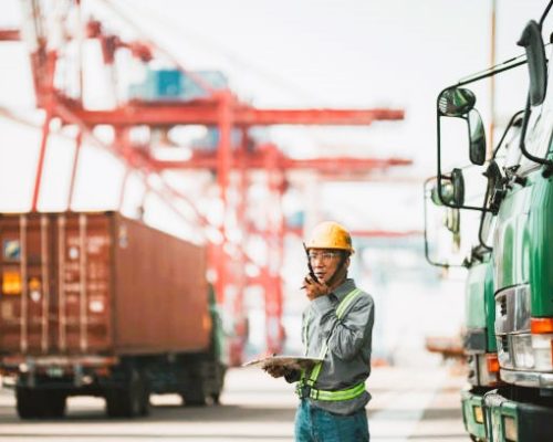 international freight forwarding Dock worker standing against cargo containers having conversation with loading control room for shipping plans